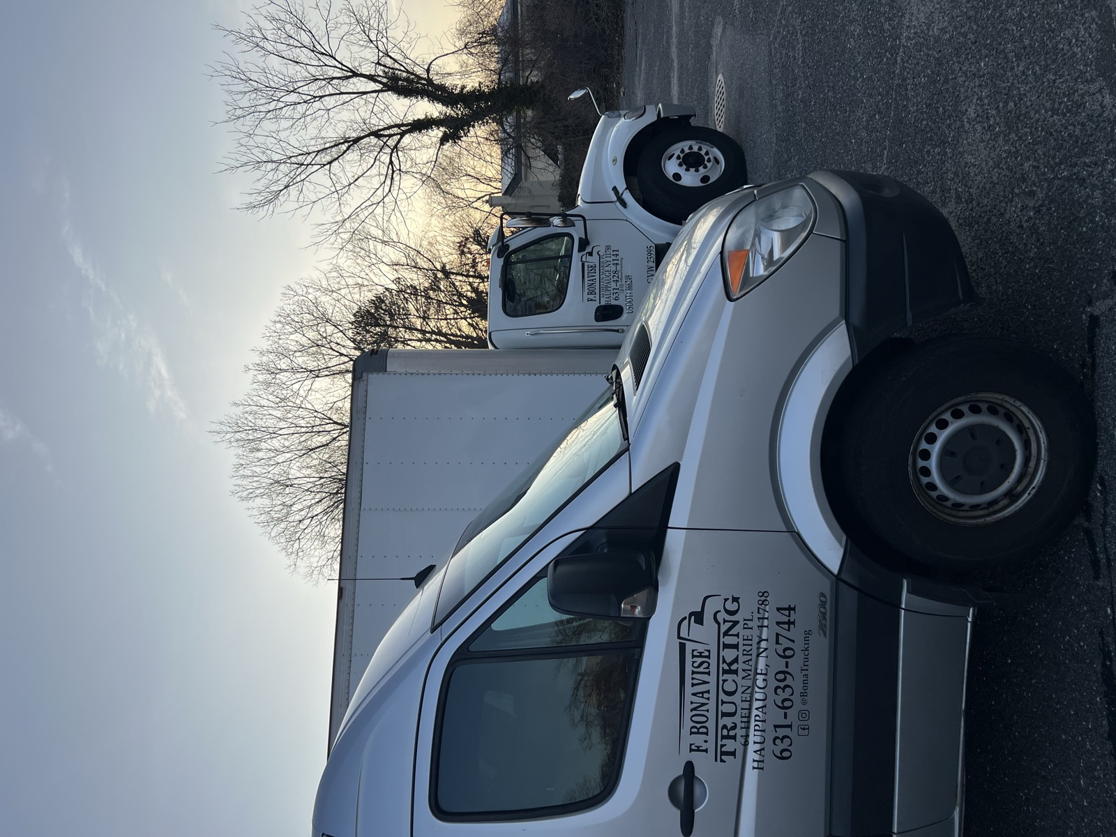 Two F. Bonavise Trucking box trucks parked at the Hauppauge yard at dusk